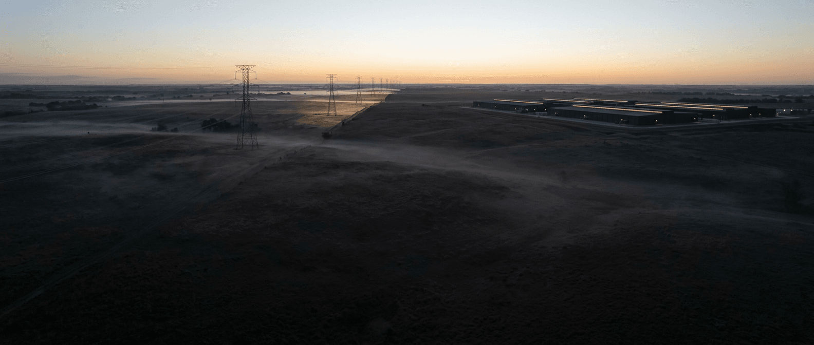 Raw ranchland at first light, a transmission corridor crossing the far boundary